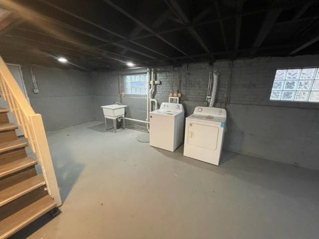 basement featuring a sink, stairway, and separate washer and dryer