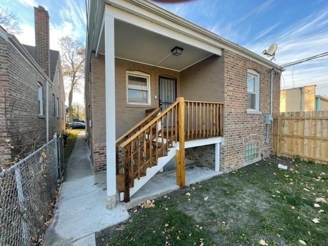 entrance to property featuring brick siding and fence