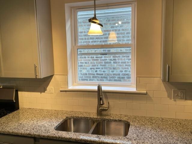 kitchen with light stone counters, a sink, and a wealth of natural light