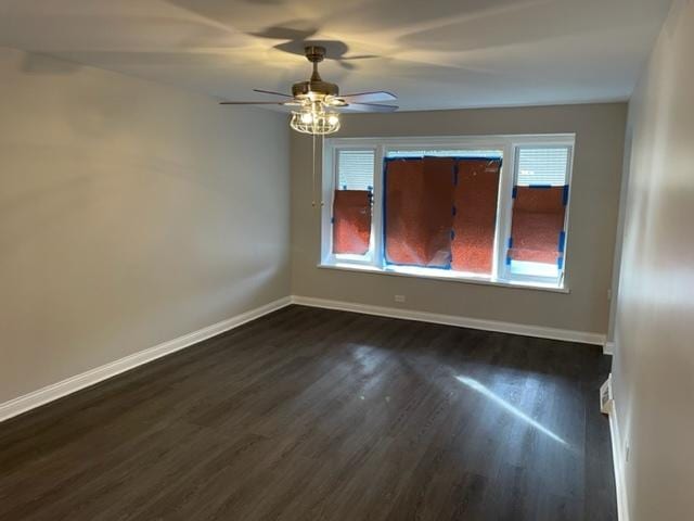 unfurnished room with dark wood-type flooring, ceiling fan, and baseboards