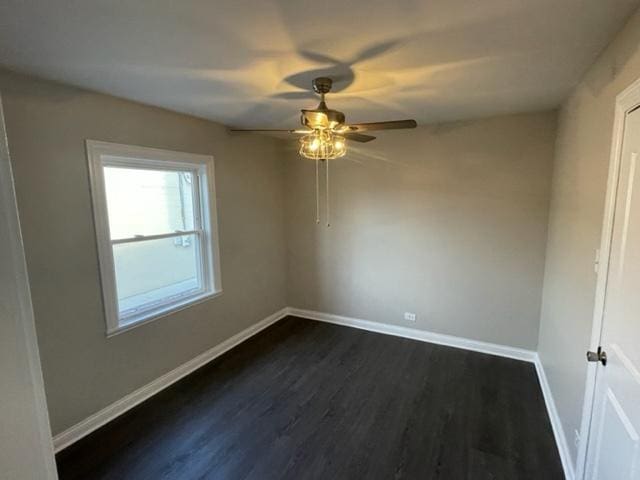 spare room with dark wood finished floors, baseboards, and ceiling fan