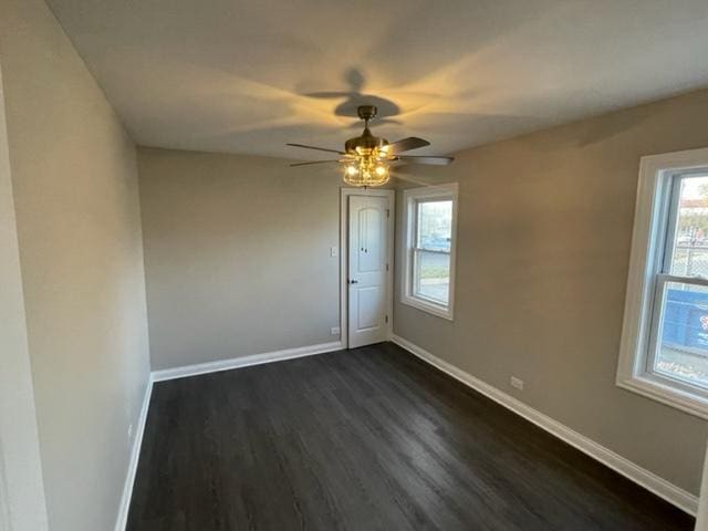 unfurnished room with dark wood-style flooring, ceiling fan, and baseboards