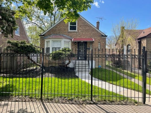 view of front facade featuring brick siding, a fenced front yard, and a front lawn