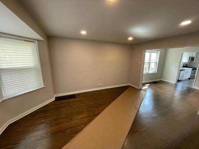 unfurnished living room featuring baseboards, visible vents, dark wood finished floors, and recessed lighting