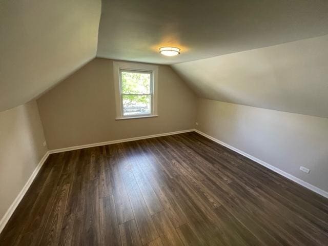 bonus room featuring dark wood-style floors, lofted ceiling, and baseboards