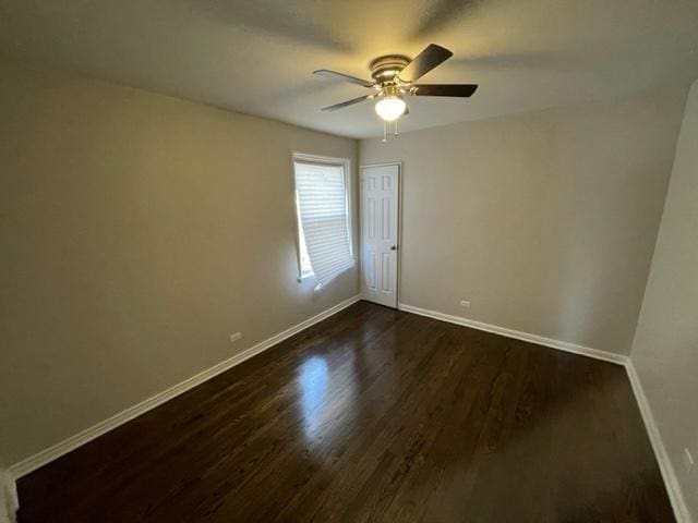 spare room featuring a ceiling fan, baseboards, and dark wood-style flooring