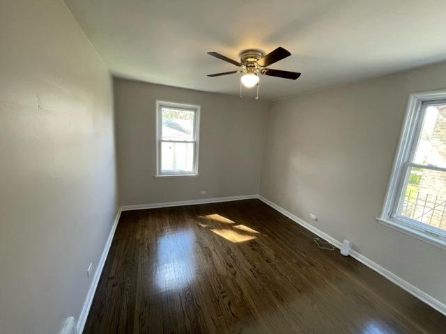 spare room featuring a ceiling fan, baseboards, and dark wood-type flooring