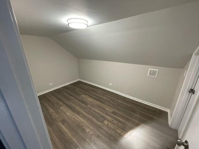 bonus room with lofted ceiling, baseboards, visible vents, and dark wood-style flooring