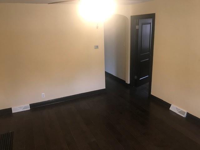 unfurnished room with dark wood-style floors, baseboards, and arched walkways