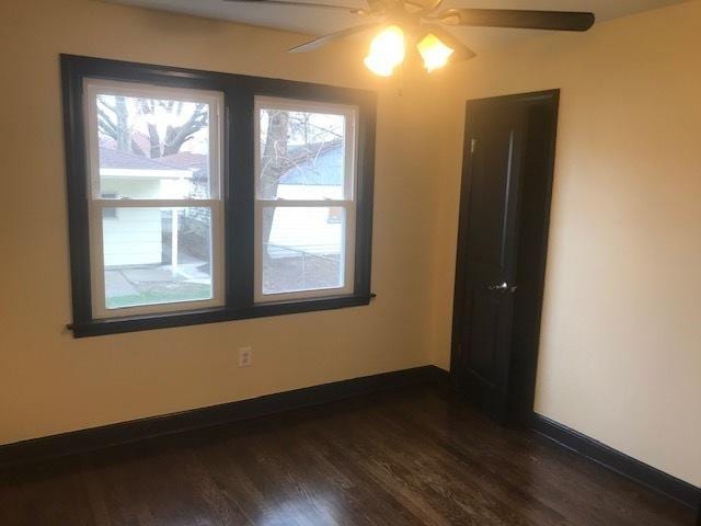 spare room featuring dark wood finished floors, baseboards, and ceiling fan