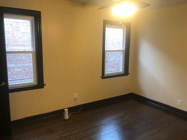 empty room featuring ceiling fan, dark wood-style flooring, and baseboards