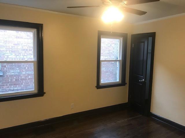 empty room with baseboards, ceiling fan, dark wood-style flooring, and crown molding