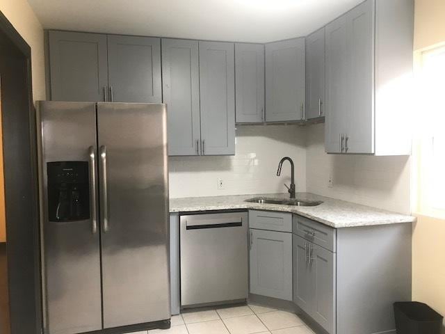 kitchen with stainless steel appliances, a sink, and gray cabinetry