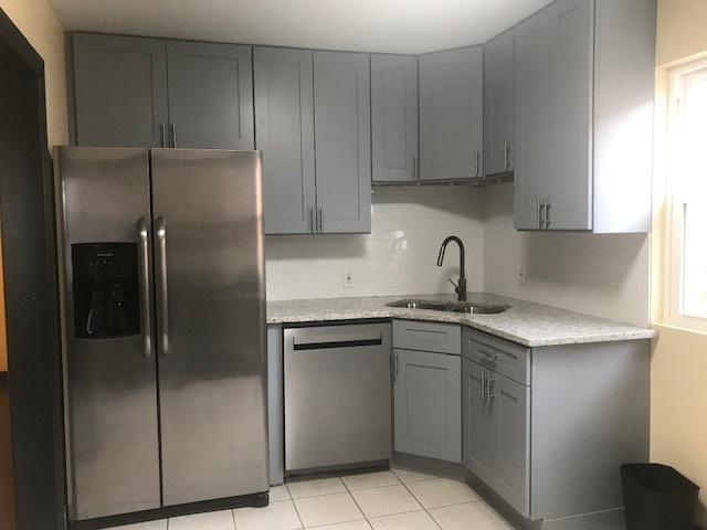 kitchen with appliances with stainless steel finishes, gray cabinets, a sink, and light stone countertops