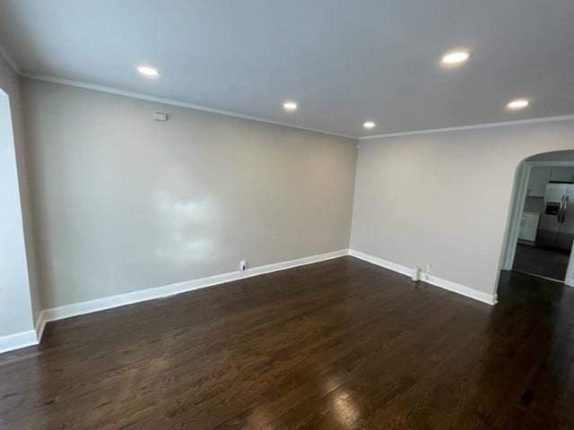 unfurnished room featuring arched walkways, dark wood-type flooring, and baseboards