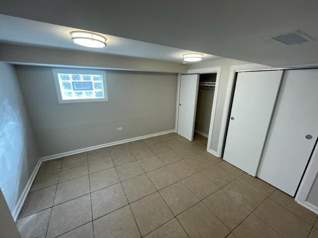 unfurnished bedroom featuring light tile patterned flooring, visible vents, baseboards, and two closets