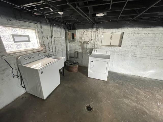 unfinished basement featuring independent washer and dryer, a sink, and electric panel