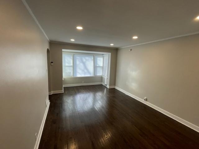 empty room with ornamental molding, arched walkways, and baseboards