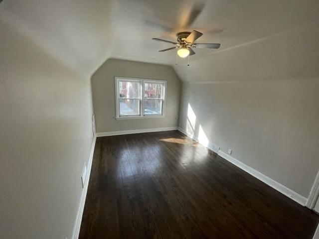 additional living space with lofted ceiling, dark wood-type flooring, a ceiling fan, and baseboards