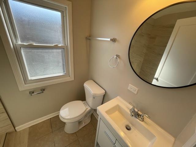 bathroom featuring toilet, vanity, baseboards, a wealth of natural light, and tile patterned floors