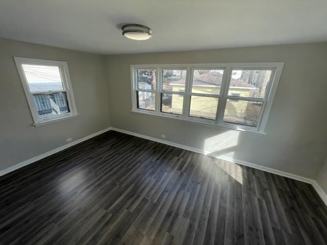 empty room featuring baseboards and dark wood finished floors