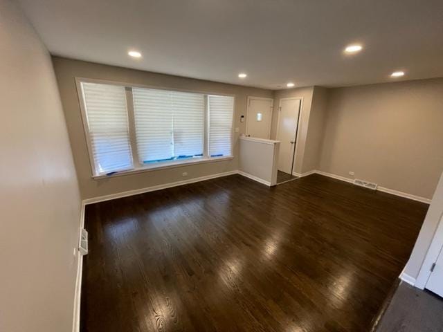 empty room featuring dark wood-style floors, visible vents, baseboards, and recessed lighting