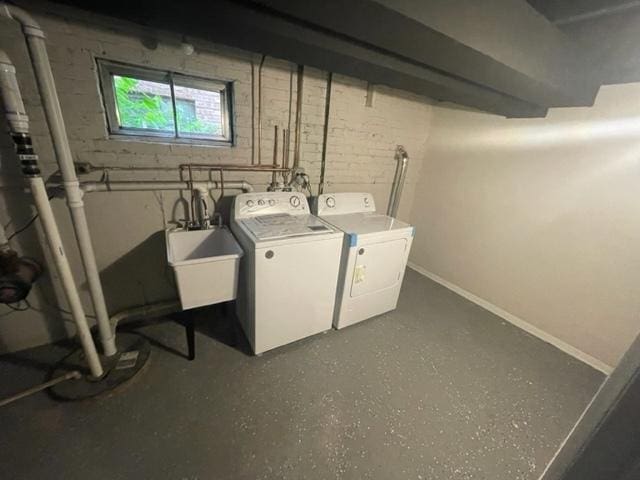 clothes washing area with baseboards, laundry area, a sink, and washer and dryer