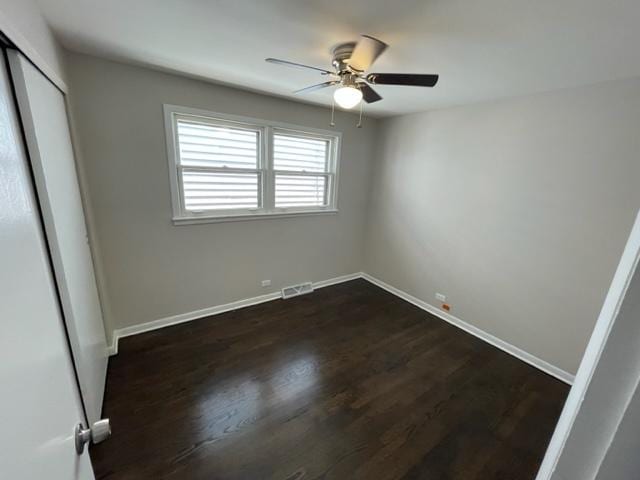 unfurnished bedroom featuring ceiling fan, visible vents, baseboards, a closet, and dark wood-style floors