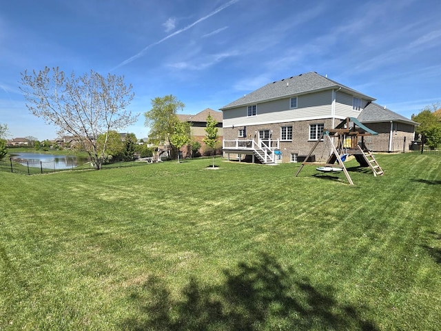 back of house featuring a playground, a deck with water view, brick siding, and stairs