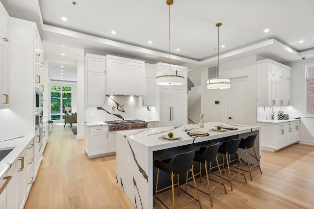 kitchen with a tray ceiling, white cabinets, pendant lighting, and a kitchen island