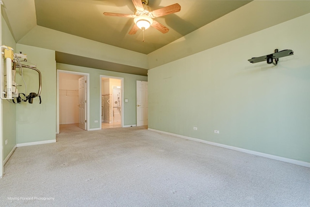 unfurnished bedroom featuring carpet, lofted ceiling, a walk in closet, ceiling fan, and a closet