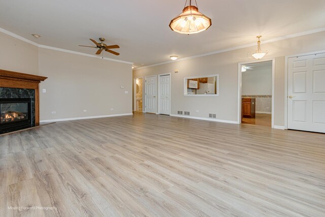 unfurnished living room with a high end fireplace, light wood-type flooring, ceiling fan, and ornamental molding