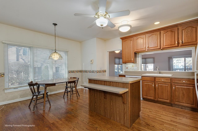 kitchen featuring ceiling fan, sink, wood-type flooring, decorative light fixtures, and a kitchen island