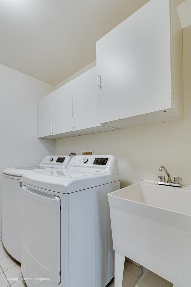 clothes washing area featuring washer and dryer, light tile patterned flooring, cabinets, and sink