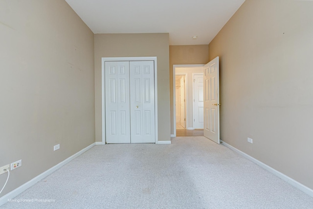 unfurnished bedroom with a closet and light colored carpet