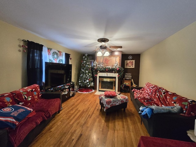 living room featuring hardwood / wood-style flooring, ceiling fan, and a tiled fireplace