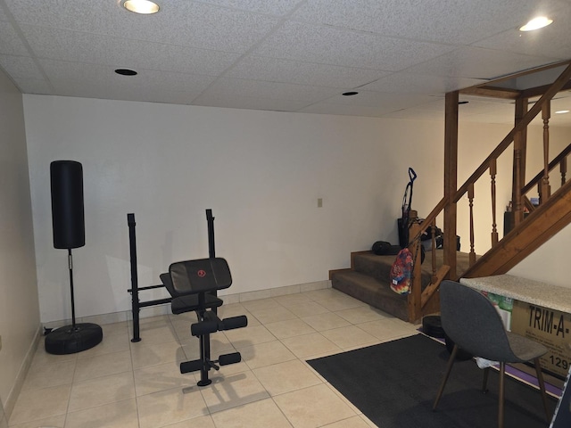 exercise room with a drop ceiling and light tile patterned flooring