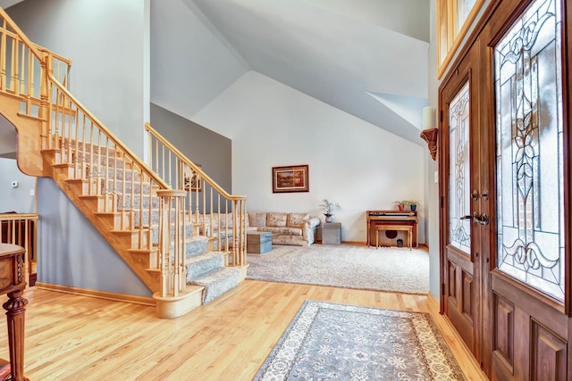 foyer entrance with high vaulted ceiling, french doors, and hardwood / wood-style flooring