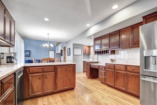 kitchen featuring stainless steel appliances, an inviting chandelier, light hardwood / wood-style floors, decorative backsplash, and pendant lighting