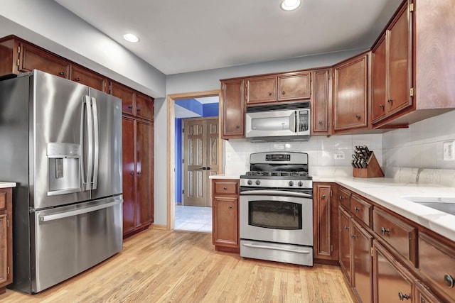 kitchen featuring appliances with stainless steel finishes, light hardwood / wood-style flooring, and backsplash