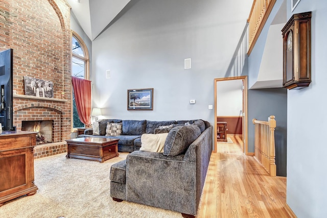 living room with high vaulted ceiling, a fireplace, and light wood-type flooring