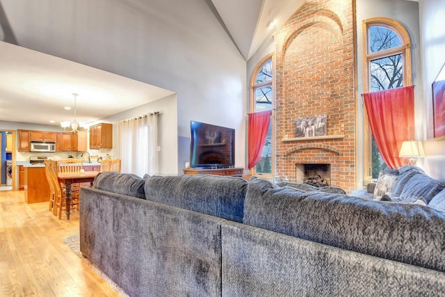 living room featuring light hardwood / wood-style floors, high vaulted ceiling, an inviting chandelier, and a wealth of natural light