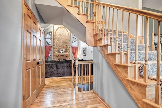 stairs featuring a brick fireplace and hardwood / wood-style flooring