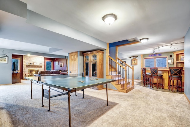 game room with a brick fireplace, carpet, and bar area