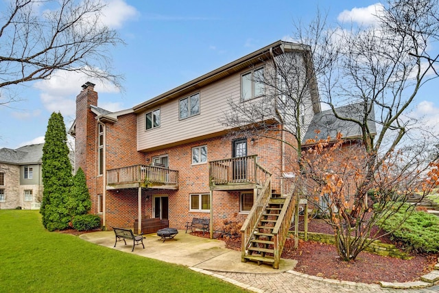 rear view of property featuring a balcony, an outdoor fire pit, a patio, and a lawn