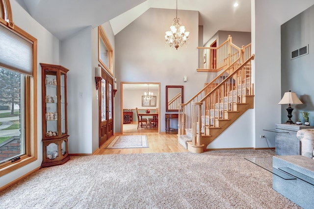 foyer featuring high vaulted ceiling, a chandelier, and light colored carpet