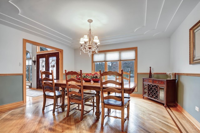 dining area featuring an inviting chandelier, french doors, light hardwood / wood-style flooring, and a healthy amount of sunlight