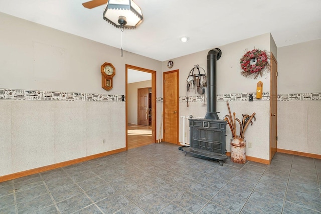 living room with a wood stove, ceiling fan, and tile walls