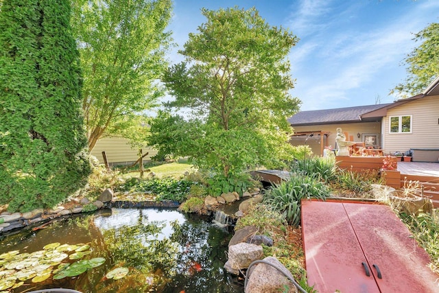 view of yard featuring a wooden deck and a small pond