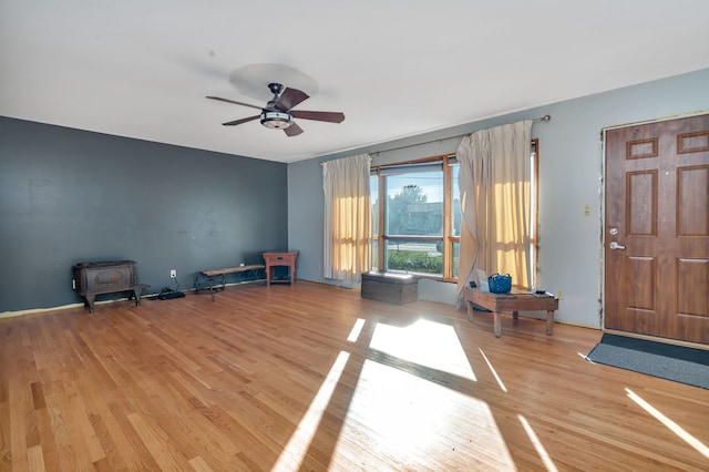 interior space featuring ceiling fan, a wood stove, and light hardwood / wood-style flooring